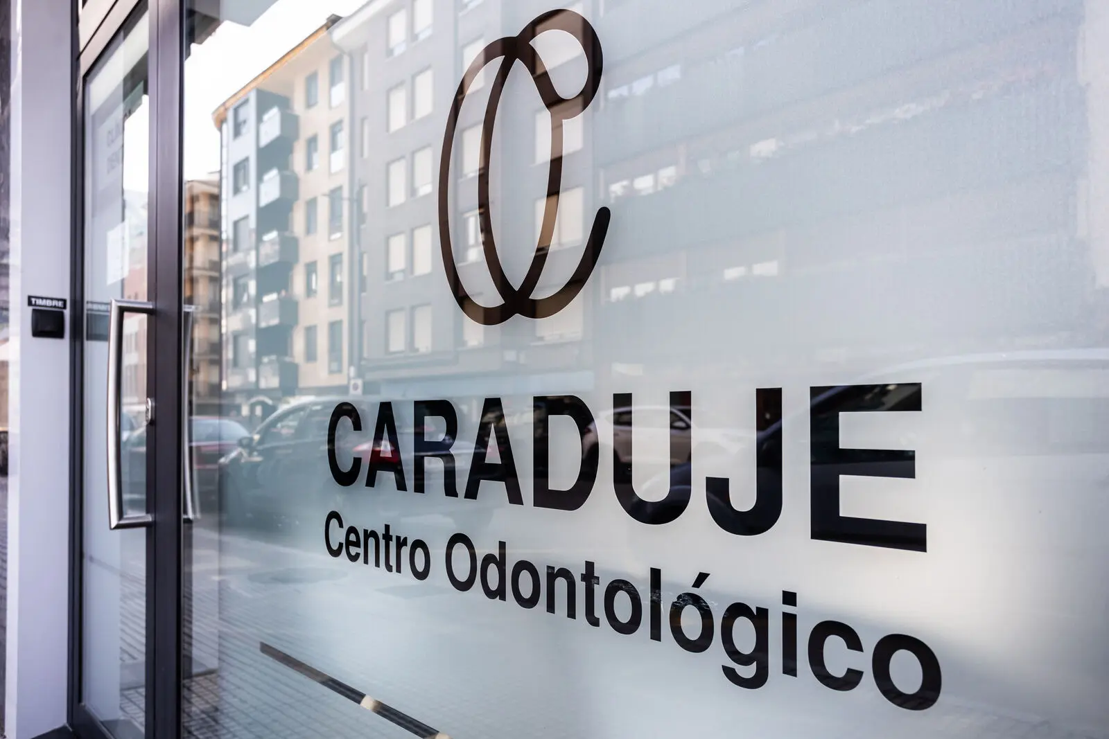 Puerta de cristal de la clínica con el rótulo Caraduje · Centro Odontológico